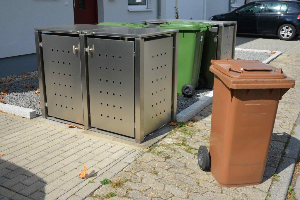 Mülltonnenbox vor einem weißen Haus 