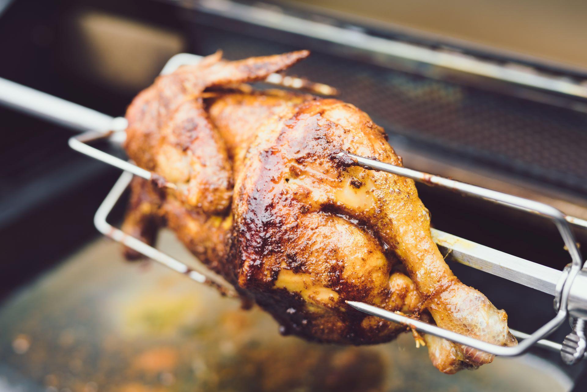 Gegrilltes Hähnchen auf einem Drehspieß im Hähnchengrill