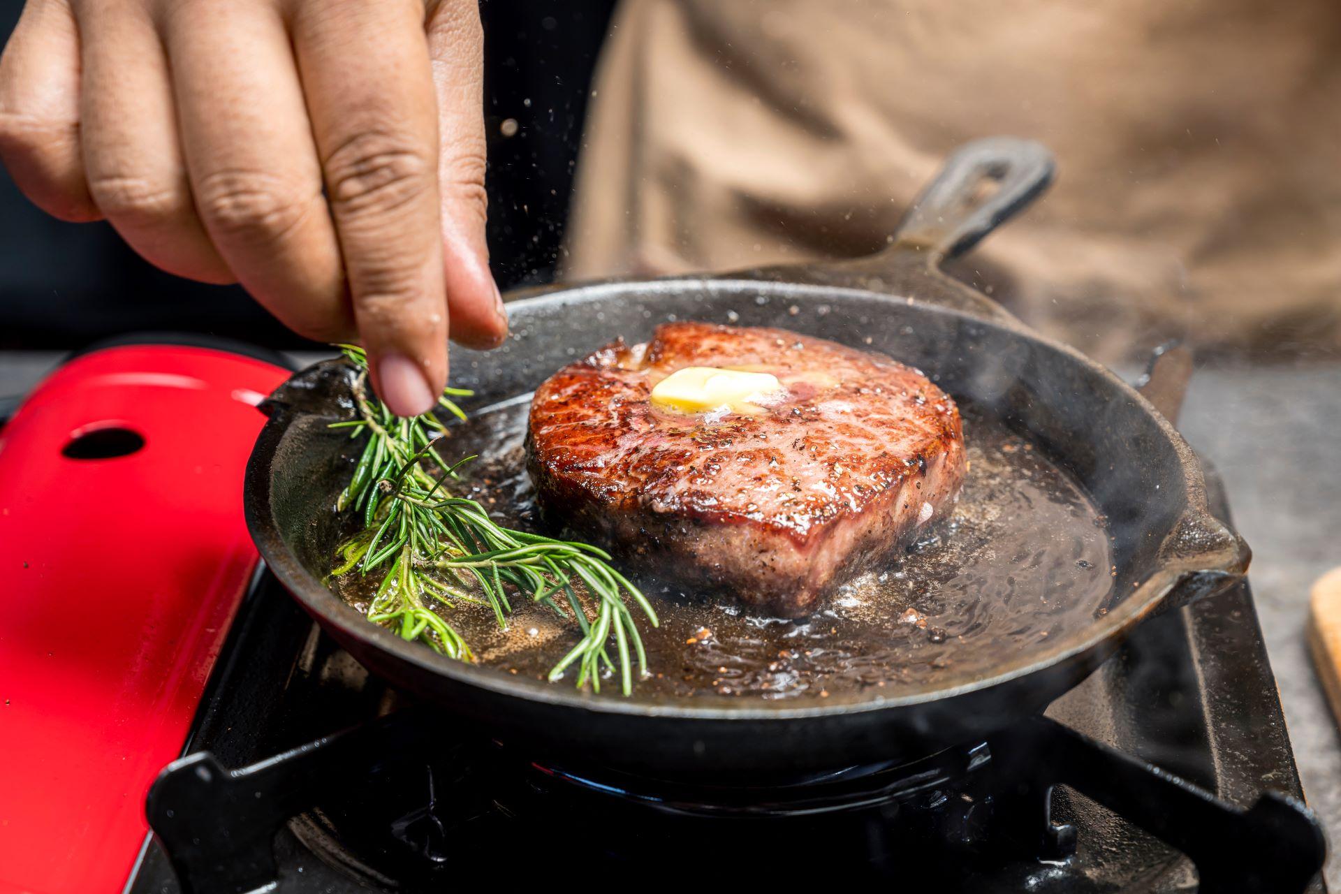 Steak mit Butter und Rosmarin in einer heißen Pfanne