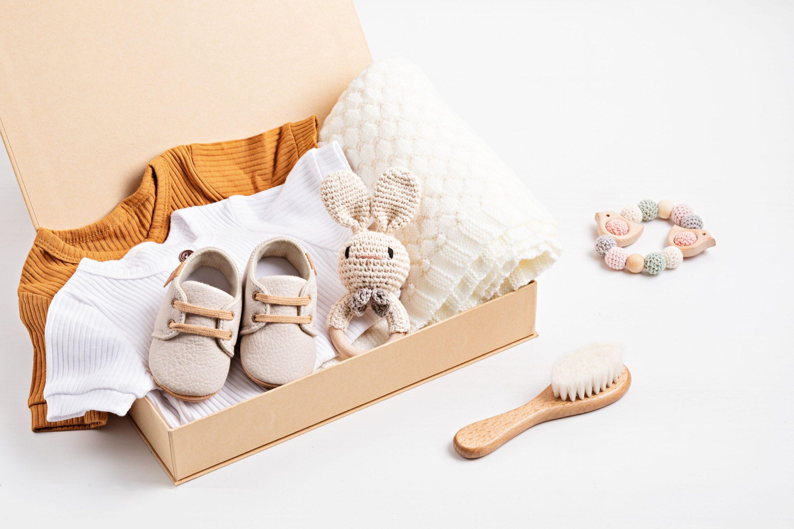 Liebevoll gestaltete Geschenkbox mit Babyschuhen, Decke, gestricktem Spielzeug und Babybürste