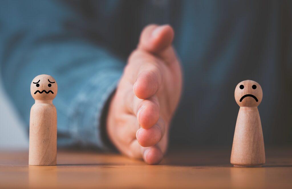 Hand trennt zwei Holzfiguren mit Gesichtern | Scheidung Ablauf